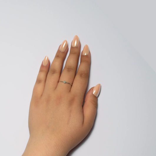 A hand curled into a loose fist against a plain white background, displaying short almond nude shimmer press on nails.