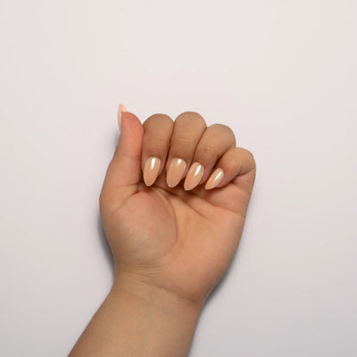 A box of Lashnetix 'Instant Manicure' press-on nails against a white background. The packaging is cream-colored with gold floral sketches and displays short almond nude shimmer nails through a clear window.
