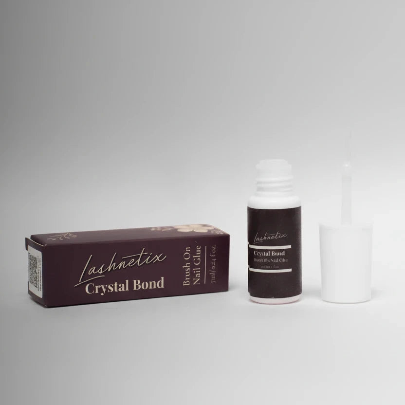 Lashnetix Crystal Bond brush-on nail glue, 7ml / 0.24 fl oz, displayed alongside its burgundy outer box with gold floral detailing on a soft grey background.